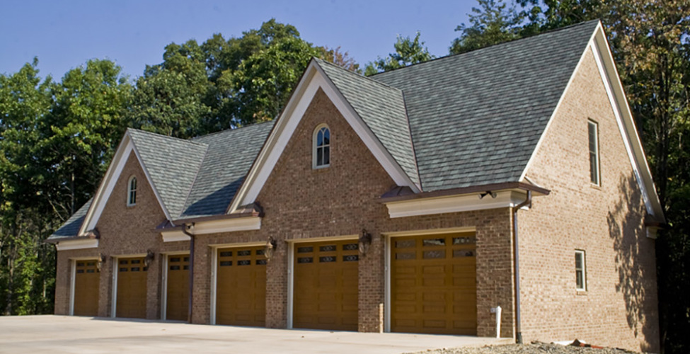 Custom carriage doors, copper gutters, Grand Manor roof, brick on all sides.